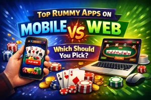 Vibrant digital illustration comparing mobile and web rummy apps. On the left, a hand holds a smartphone showing a rummy game with poker chips and coins around it against a blue background. On the right, a laptop displays a rummy table with cards, chips, and a mouse on a green background. Bold text reads 'Top Rummy Apps on Mobile vs Web' with a fiery 'VS' and the question 'Which Should You Pick?'.